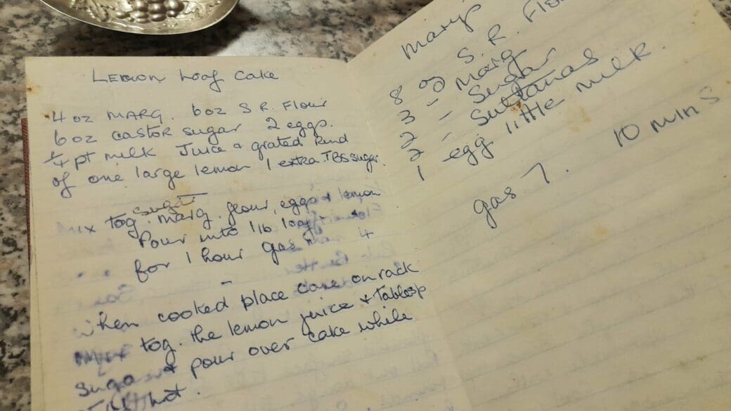 Recipe for a lemon loaf cake written on a line-page noteboo. It has stains and marks from food debris. It's written in blue ink, that's beginning to fade.