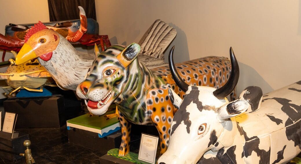 A display of Ghanaian fantasy coffins shaped like animals, including a rooster, leopard and cow.