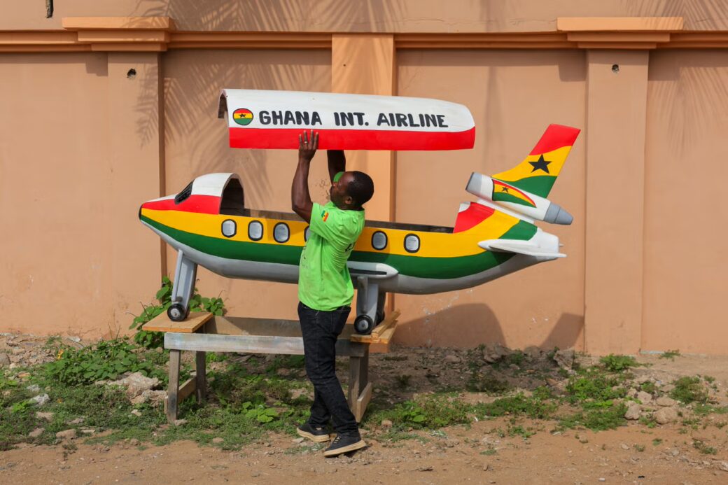 A man lifts part of a Ghana International Airline plane-shaped fantasy coffin outside a workshop.